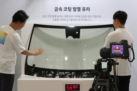 A visitor to Hyundai Motor's Heat Tech Day looks at a windshield equipped with a metal-coated heating glass technology designed to reduce the amount of time required to remove frost and moisture. [YONHAP]