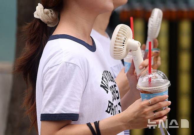 [서울=뉴시스] 김명년 기자 = 절기상 더위가 그친다는 처서인 22일 오후 서울 종로구 광화문사거리에서 시민들이 아이스 커피와 휴대용 선풍기를 들고 길을 지나가고 있다. 2024.08.06. kmn@newsis.com