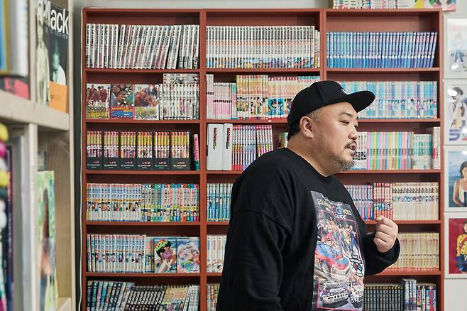 김봉현씨가 자신이 수집한 만화책들이 진열된 책장 앞에 서 있다. 스튜디오 어댑터 염서정