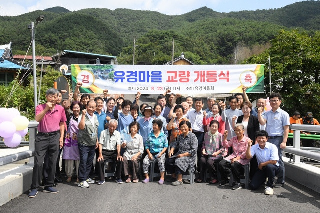 정영균 전남도의원이 지난 23일 송광면 삼청리 유경마을 교량 개통식에 참석해 마을 주민들로부터 교량 개선 사업에 기여한 공로를 인정받아 감사패를 수여받은 뒤 주민들과 기념촬영했다. 전남도의회 제공