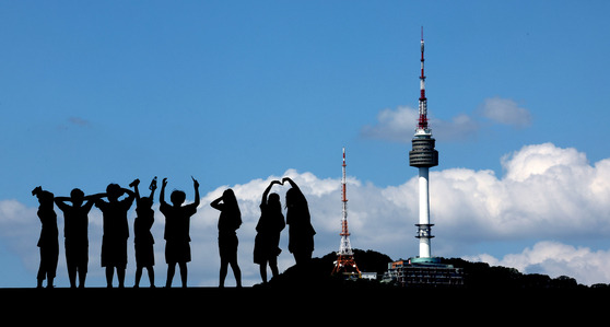 People enjoy the view of the clear blue sky and N Seoul Tower at the National Museum of Korea in Yongsan District, central Seoul, on Wednesday. Although Seoul continues to experience hot afternoons, morning and evening breezes bring cooler temperatures. [NEWS1]