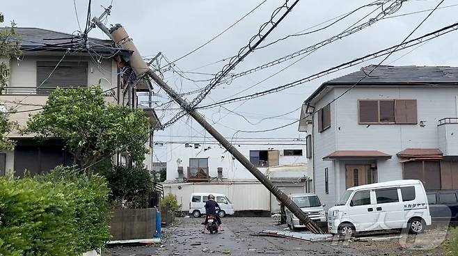 태풍 산산이 일본을 덮친 29일 일본 미야자키에서 한 시민이 쓰러진 전신주 사이로 지나가고 있다. ⓒ 로이터=뉴스1 ⓒ News1 신웅수 기자