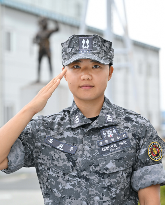 해군이 30일 열린 해난구조전대(SSU) 해난구조 기본과정 수료식에서 장교 9명, 부사관 24명, 병 31명 등 교육생 64명이 수료하고 심해잠수사가 됐다고 밝혔다. 이 가운데 대위 진급이 예정된 문희우 해군 중위는 여군 최초로 심해잠수사 휘장을 거머쥐었다. 사진은 문희우 해군 중위가 ‘세계최강 SSU’ 동상 앞에서 경례하는 모습. 2024.8.30 해군 제공