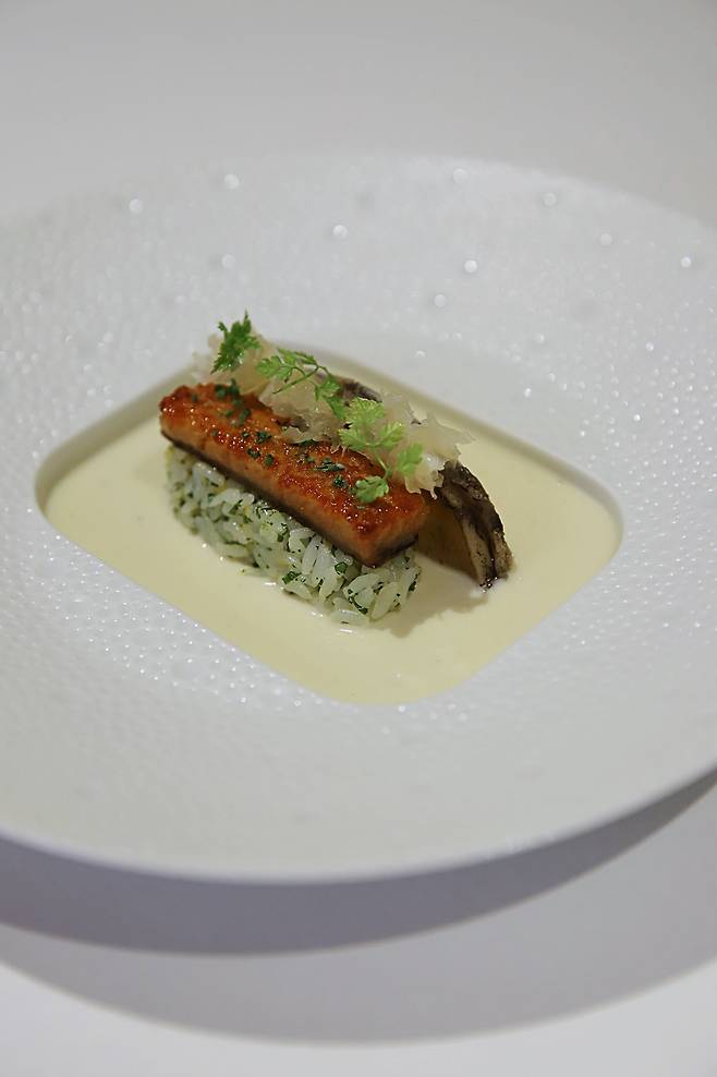 The abalone and eel menu. The dish showcases tender steamed eel atop perfectly cooked rice, enriched with truffle paste and olive oil. The aromatic hints of lemon and parsley provide a refreshing contrast to the savory flavors./L’Amitié