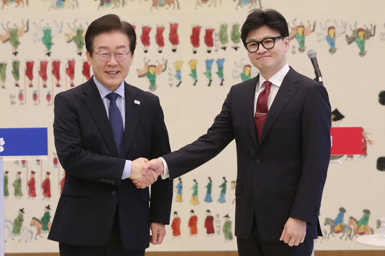 Democratic Party (DP) leader Lee Jae-myung, left, and People Power Party (PPP) leader Han Dong-hoon shake hands ahead of their official talks held at the National Assembly in Yeouido, western Seoul, on Sunday. [NEWS1]