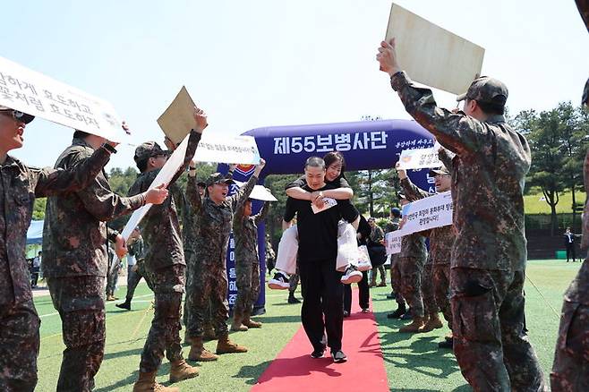 [서울=뉴시스] 14일 55사단(경기 용인)에서 병무청 주관으로 열린 현역병 입영문화제에서 입영대상자가 부모님을 업고 '감사&사랑'의 길을 지나고 있다. (사진=병무청 제공) 2024.05.14. photo@newsis.com *재판매 및 DB 금지