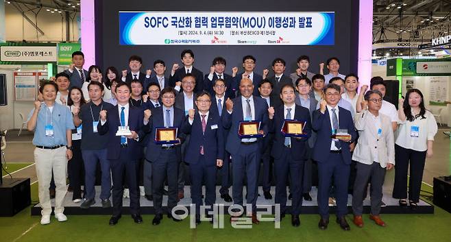 4일 부산 BEXCO에서 열린 SOFC 국산화 협력 이행성과 발표회에서 SK에코플랜트와 한국수력원자력, 블룸에너지, 블룸SK퓨얼셀 관계자들이 기념촬영을 하고 있다(앞줄 왼쪽 3번째부터 김정훈 SK에코플랜트 솔루션BU 대표, 윤상조 한국수력원자력 그린사업본부장, 사티시 치투리(Satish Chitoori) 블룸에너지 COO(Chief Operations Officer), 김세준 블룸SK퓨얼셀 부사장). (사진=SK에코플랜트)