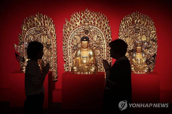 목조석가모니삼존상 앞에서 (서울=연합뉴스) 강민지 기자 = 4일 오전 서울 종로구 불교중앙박물관에서 열린 특별전 '큰 법 풀어 바다 이루고, 교종본찰 봉선사' 언론 공개회에서 참석자들이 '목조석가모니삼존상'을 둘러보고 있다. 2024.9.4 mjkang@yna.co.kr