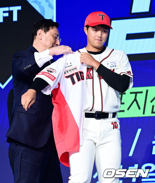 [OSEN=지형준 기자] 11일 오후 서울 잠실 롯데호텔 월드에서 2025 KBO 신인 드래프트가 열렸다.2025 KBO 신인 드래프트는 전면 드래프트 방식으로 진행된다. 지명은 1라운드부터 11라운드까지 이뤄지며, 2023년도 구단 순위의 역순인 키움-한화-삼성-롯데-KIA-두산-NC-SSG-KT-LG 순서로 실시된다.덕수고 김태형이 KIA에 1라운드 지명되며 심재학 단장이 유니폼을 전달하고 있다. 2024.09.11 / jpnews@osen.co.kr