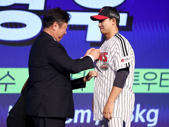 차명석 LG 단장이 11일 오후 서울 롯데호텔에서 열린 2025 KBO 신인 드래프트에서 1라운드 10순위로 서울고 김영우를 지명한 뒤 유니폼 단추를 채워주고 있다. 연합뉴스