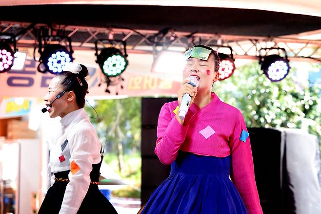 ‘인턴 각설이’ 조유미 기자가 관객에게 받은 1만원권(세종대왕)을 이마에 붙이고 ‘진이’를 열창하고 있다. 진분홍 저고리와 푸른 치마는 20년 차 각설이 고하자(왼쪽) 언니가 “어울리겠다”며 골라준 것. /주민욱 영상미디어 기자