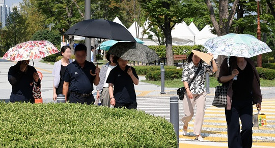 가을 폭염이 기승을 부리고 있는 가운데 지난 11일 서울 여의도 국회에서 시민들이 양산을 쓰고 이동하고 있다. 사진=뉴시스