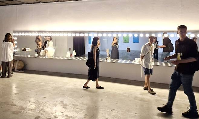 ▲본전시 제1전시실의 미라 만 작 '바람의 사물', 2024. 거울, 조명, 스테인리스 강 선반, 진도 북, 다양한 사물 및 인쇄물, 110×960×35cm, 40분. [작가 및 드라이 갤러리 (쾰른), N/A 갤러리 (서울)], 제15회 광주비엔날레 커미션