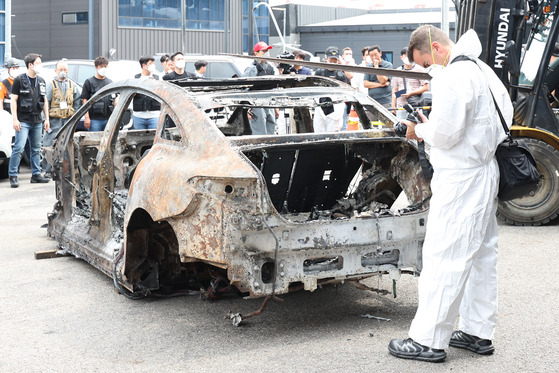 A Mercedes-Benz executive examines the burnt Mercedes EQE sedan in Incheon on Aug. 8. The Mercedes EQE EV explosion damaged as many as 880 vehicles parked in the garage. [NEWS1]