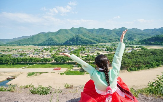 한복을 곱게 차려입은 한 관광객이 안동하회 마을을 바라보며 포즈를 취하고 있다(안동시 제공)