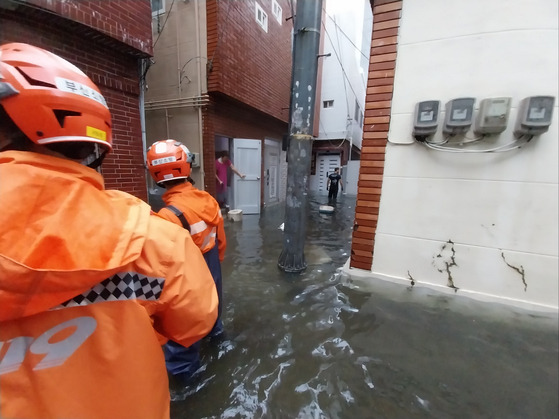 21일 오전 부산 진구 범천동 주택가 골목과 집 안이 침수돼 소방대원이 배수 활동을 벌이고 있다. 〈사진=부산소방재난본부〉