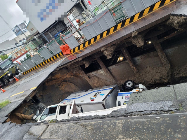 21일 오전 부산 사상구 한 도로에서 가로 10m, 세로 5m, 깊이 8m 가량의 대형 땅꺼짐 현상(싱크홀)이 발생해 도로에서 배수 지원을 하던 삼락119안전센터 배수 차량과 5톤 트럭이 빠져있다. 제공=부산경찰청, 뉴스1