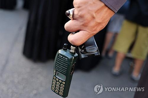 레바논 무전기 동시다발 폭발 (베이루트 AFP=연합뉴스) 18일(현지시간) 레바논 베이르트 인근에서 전날 삐삐 폭발로 사망한 주민의 장례식이 열린 가운데 한 참석자가 폭발 위험 때문에 배터리를 제거한 무전기를 손에 들고 있다. 전날 레바논 곳곳에서 헤즈볼라 통신수단인 삐삐 수천대가 터진 데 이어 이날은 무전기가 폭발해 이틀한 40명 가까이 숨지고 3천여명이 다쳤다.