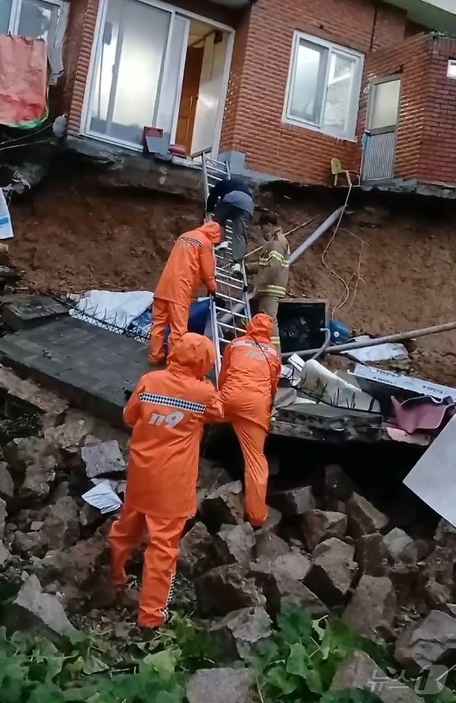 21일 부산진구 연지동 한 주택 담벼락이 무너지면서 2명이 고립돼 소방대원이 구조하고 있다.(부산소방재난본부 제공)