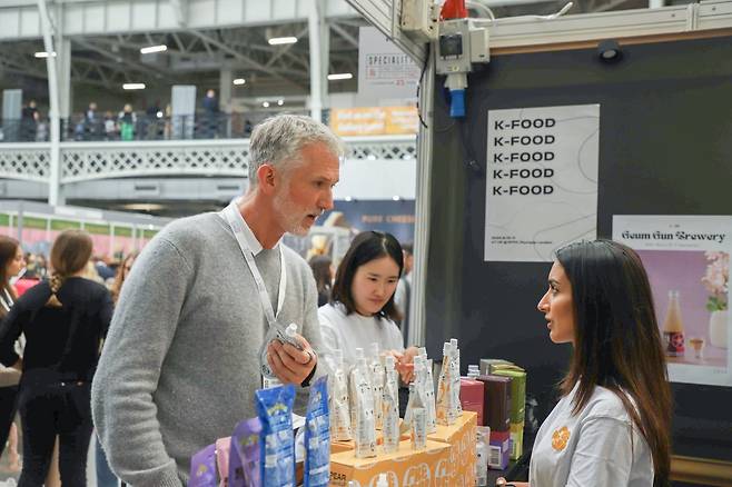 지난 10~11일(현지 시각) 영국 런던 올림피아에서 열린 ‘2024 SFFF(Speciality & Find Food Fair)’의 한국 부스에 한국 홍보 제품들이 전시돼 있다. 한국 나주산 배로 만든 파우치형 배 주스 ‘프리페어(prepear)’에 관심을 보이는 참가자의 모습이 보인다. /한국농수산식품유통공사(aT) 제공