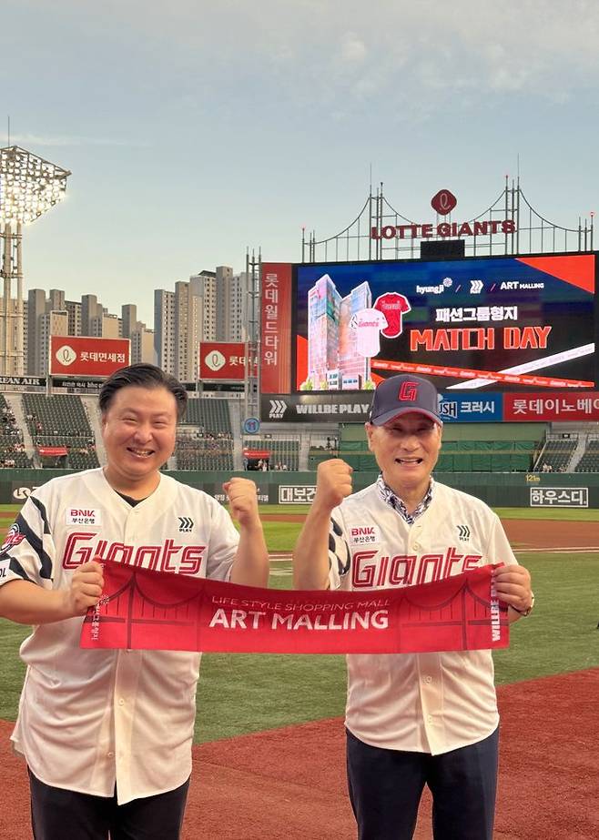 19일 롯데자이언츠와 LG트윈스 경기가 열린 부산 사직야구장에서 패션그룹형지 최병오 회장(오른쪽)과 최준호 부회장(왼쪽)이 응원 머플러를 들고 포즈를 취하고 있다. 이날 경기는 '패션그룹형지 매치데이'로 진행됐으며 최병오 회장이 시구를 했다.ⓒ형지엘리트
