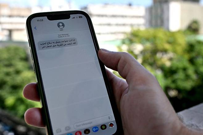 한 레바논 남성이 23일(현지시간) 베이루트에서 자신의 휴대폰으로 수신된 메시지를 보여주고 있다. 메시지의 내용은 ‘헤즈볼라가 무기를 숨겨놓은 곳에서부터 대피하라’로, 이스라엘이 보낸 것으로 추정된다. AFP연합뉴스
