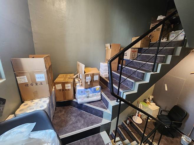 C 호텔 비상계단 계단 한쪽에 각종 비품을 둬 창고처럼 사용하고 있다. 아래쪽엔 의자와 선풍기 등으로 직원 휴게공간을 마련했다. [촬영 장종우]
