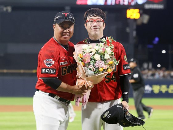 25일 롯데전에서 10년 연속 170이닝 투구를 달성한 뒤 이범호 감독(왼쪽)에게 축하 꽃다발을 받은 양현종. 연합뉴스