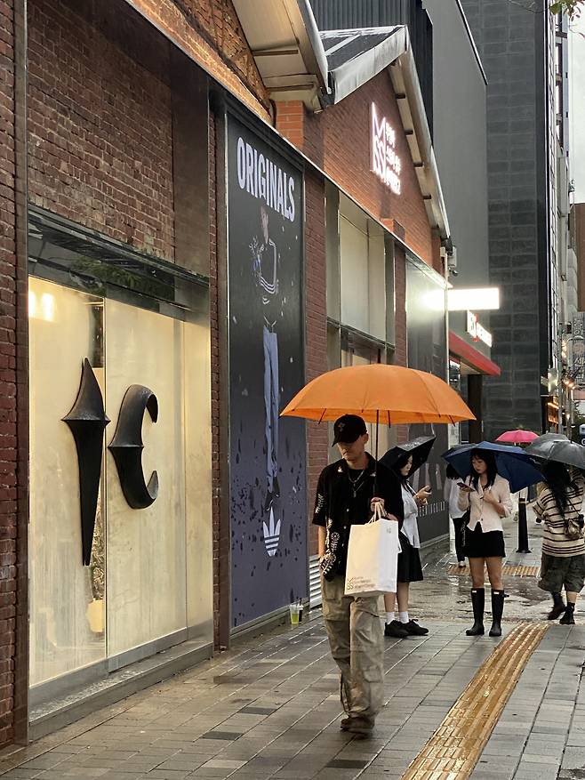 Visitors to Seongsu street walk with umbrellas past the front of Musinsa Store Seongsu @DaerimChanggo on Sept. 20.(Hwang Joo-young/The Korea Herald)