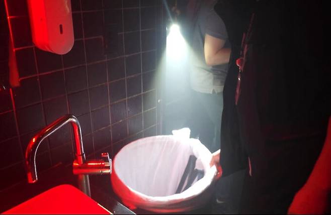 경찰 관계자가 클럽 화장실 쓰레기통을 살펴보고 있다.&nbsp;