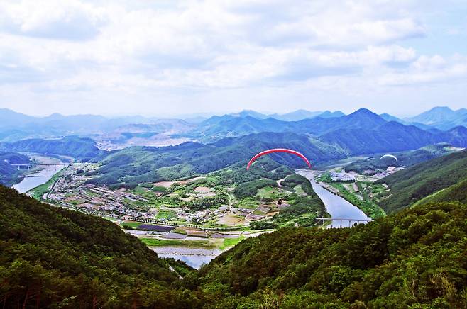 두산활공장에서부터 날아올라 패러글라이더를 타는 사람들. 강을 사이에 두고 왼쪽으로 이어지는 마을이 덕천리, 오른쪽 마을이 사평리다.