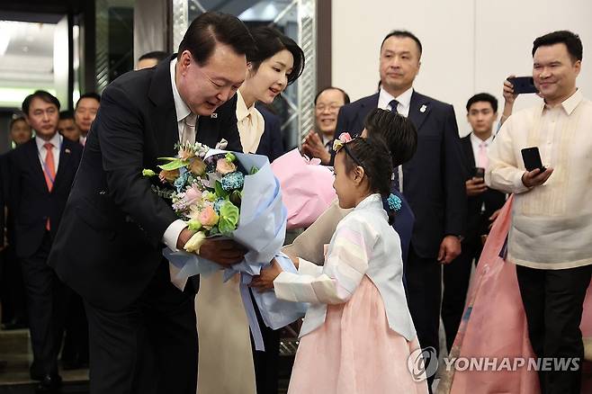 화동으로부터 꽃다발 받는 윤석열 대통령 부부 (마닐라=연합뉴스) 진성철 기자 = 필리핀을 국빈 방문한 윤석열 대통령과 김건희 여사가 6일 오후(현지시간) 필리핀 마닐라 페닌슐라 호텔에서 열린 동포 만찬 간담회에 참석해 화동으로부터 꽃다발을 받고 있다. 2024.10.6 zjin@yna.co.kr