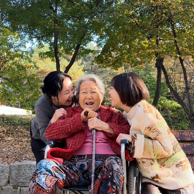 치매 걸린 할머니와의 일상을 담은 에세이집 '우리는 서로의 얼굴을 오래 보았다'를 쓴 김영롱(오른쪽부터)씨와 그의 할머니 노병래씨, 엄마 구숙희씨가 공원에서 산책을 하며 활짝 웃고 있다. 김영롱씨 제공