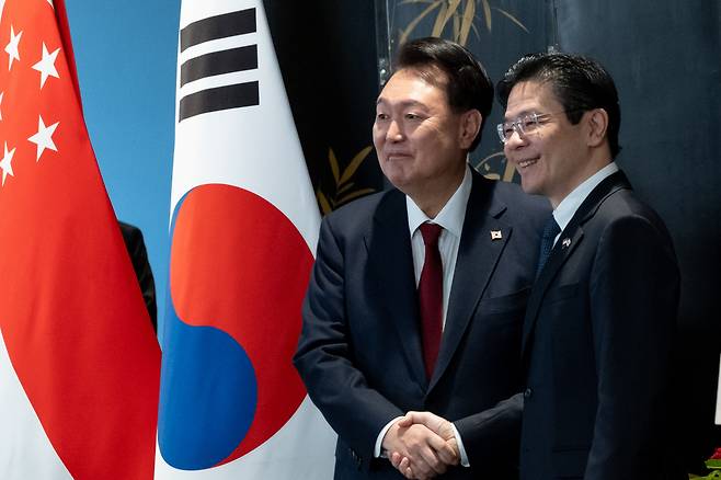 President Yoon Suk Yeol (left) shakes hands with Singaporean Prime Minister Lawrence Wong after a joint press conference on Tuesday at the Parliament House of Singapore. (Pool photo via Yonhap)