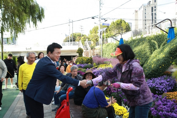 박준희(왼쪽) 서울 관악구청장이 신원시장 달빛축제 인근 국화꽃 정원에서 주민과 악수하고 있다.   관악구 제공