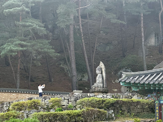 지난 9월 30일 한 탐방객이 경주 동남산 미륵곡 석조여래좌상에게 기도를 올린 뒤 기념 촬영을 하고 있다. 김홍준 기자