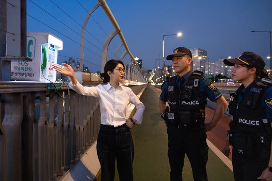 김건희 여사가 지난달 10일 '세계 자살 예방의 날'을 맞아 서울 마포대교에서 마포경찰서 용강지구대 근무자와 함께 '생명의 전화'를 살펴보며 대화하고 있다. 사진 대통령실