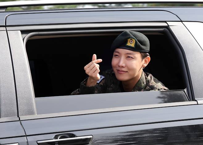 J-Hope of boy band BTS makes a finger heart to fans as he leaves his base camp in Wonju, Gangwon, after finishing his mandatory military duty on Oct. 17. [YONHAP]