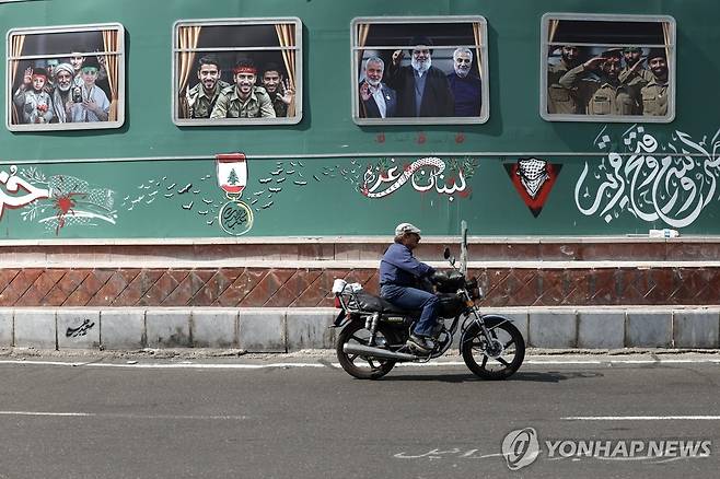 7일(현지시간) 이란 테헤란 광장에 걸린 하마스, 헤즈볼라, 이란 혁명수비대 산하 쿠드스군 사령관 광고물 앞을 지나는 오토바이.  [EPA 연합뉴스 자료사진. 재배포 및 DB 금지]