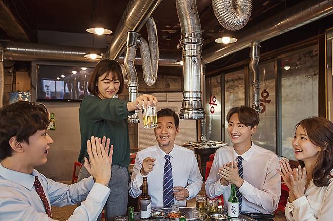 A person holds a glass of beer in a restaurant with her colleagues. [GETTY IMAGES BANK]