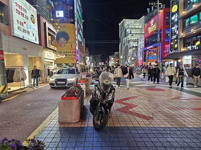 지난 20일 저녁 서울 마포구 홍대축제거리(레드로드)에서 행인들이 불법 주차된 대형 승합차를 피해 걷고 있다. 이곳은 주말 동안 ‘차 없는 거리’로 운영되지만 차량 통행과 불법 주차가 상시적으로 이뤄지고 있다. [지혜진 기자]