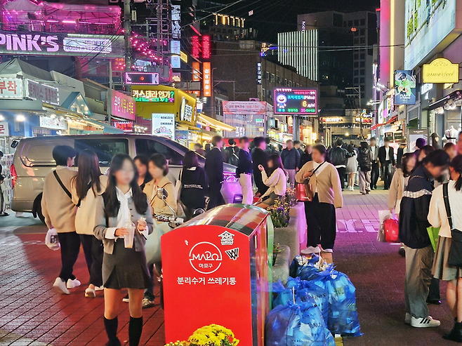 지난 20일 저녁 서울 마포구 홍대축제거리(레드로드)에서 행인들이 불법 주차된 대형 승합차를 피해 걷고 있다. 이곳은 주말 동안 ‘차 없는 거리’로 운영되지만 차량 통행과 불법 주차가 상시적으로 이뤄지고 있다. [지혜진 기자]