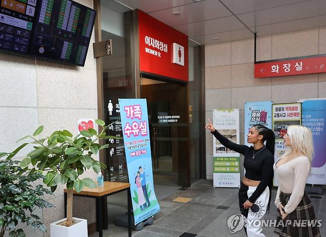 망향휴게소 화장실 전광판 보는 외국인 이용객들 [촬영 이주형]