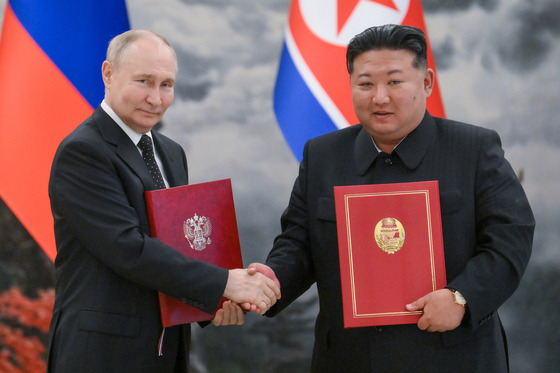 Russian President Vladimir Putin and North Korean leader Kim Jong-un hold two copies of the new treaty between the two countries after signing them in Pyongyang, June 19. [TASS/YONHAP]