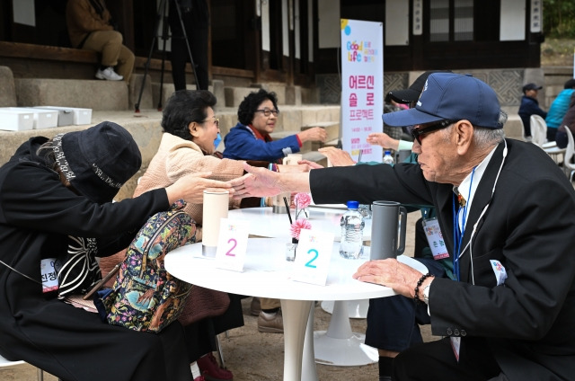 23일 서울 종로구 운현궁 앞에서 진행된 ‘굿 라이프 챌린지’에 참가한 어르신들이 테이블에 마주 앉아 악수하며 인사를 하고 있다. 이 행사는 65세 이상 어르신을 대상으로 한 커플 매칭 프로그램이다. 윤웅 기자