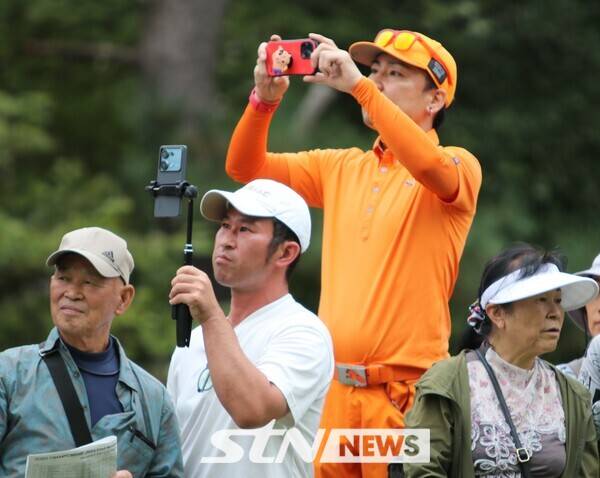 '오렌지 보이'로 유명한 리키 파울러의 시그니처 의상을&nbsp; 입고 일본 팬이 파울러의 티샷 영상을 찍고 있다. 사진┃STN NEWS