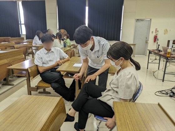 일본 류큐대 의대 재학생인 시마부쿠로 쇼고(23) 씨와 킨조 나기사(25) 씨가 지난해 9월 오키나와현의 한 섬 지역에 의료 봉사를 하던 중 학생들 앞에서 간단한 의료 실습을 선보이고 있다. 사진 나기사 씨 제공
