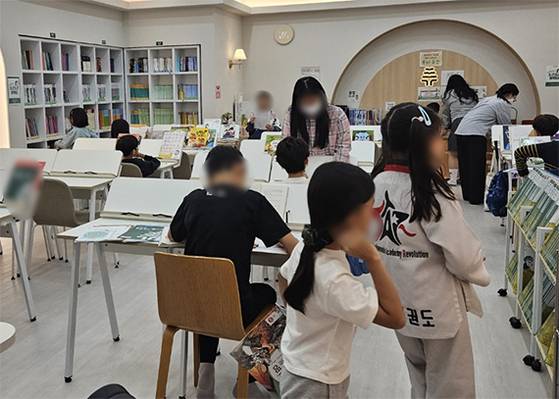‘AI 디지털 교과서’ 도입을 앞두고 서울 강남구 대치동의 한 문해력 학원을 찾은 학부모와 학생들이 읽을 책을 고르고 있다. 신수민 기자