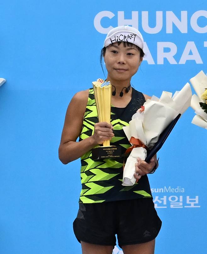 27일 강원도 춘천에서 열린 '2024 조선일보 춘천마라톤'. 마스터스 여자 부문 1위 최미경씨가 트로피와 상장을 받고 있다. /고운호 기자