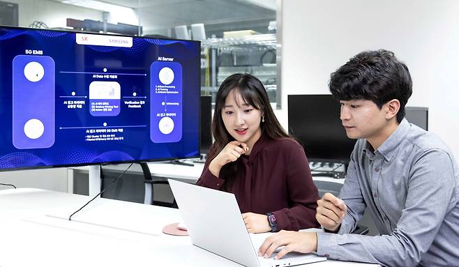 SK텔레콤과 삼성전자 연구원이 AI 기반 5G 기지국 품질 최적화 기술 실증에 대해 논의하는 모습. /SK텔레콤 제공